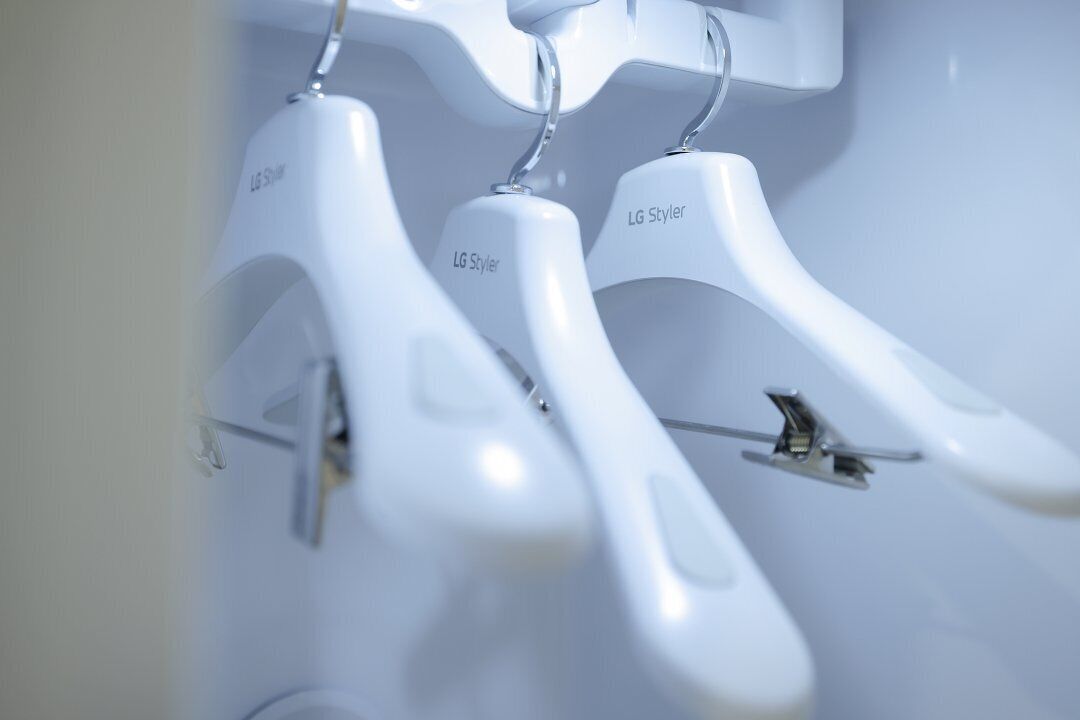 White plastic hangers labeled "LG Styler" on a wall.