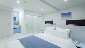 A modern hotel room with a large bed, a bedside table, a nightstand, a mirror, and a bathroom visible through an open door. - Anook Air Hotel Jinju (Jinju)