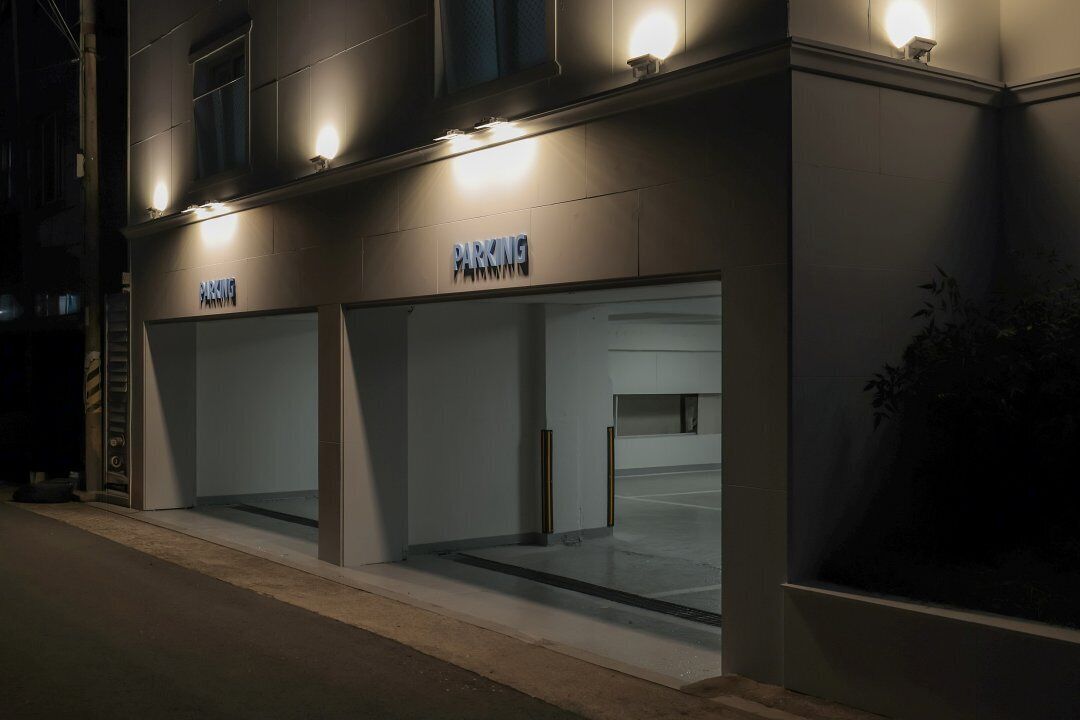 A building with two illuminated 'PARKING' signs, suggesting a parking facility.