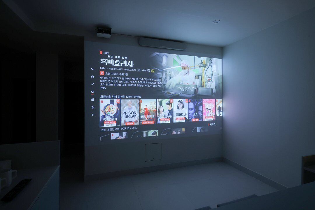 Eine projizierte Leinwand zeigt eine Filmsuchansicht in einem stilvoll reduzierten Raum.