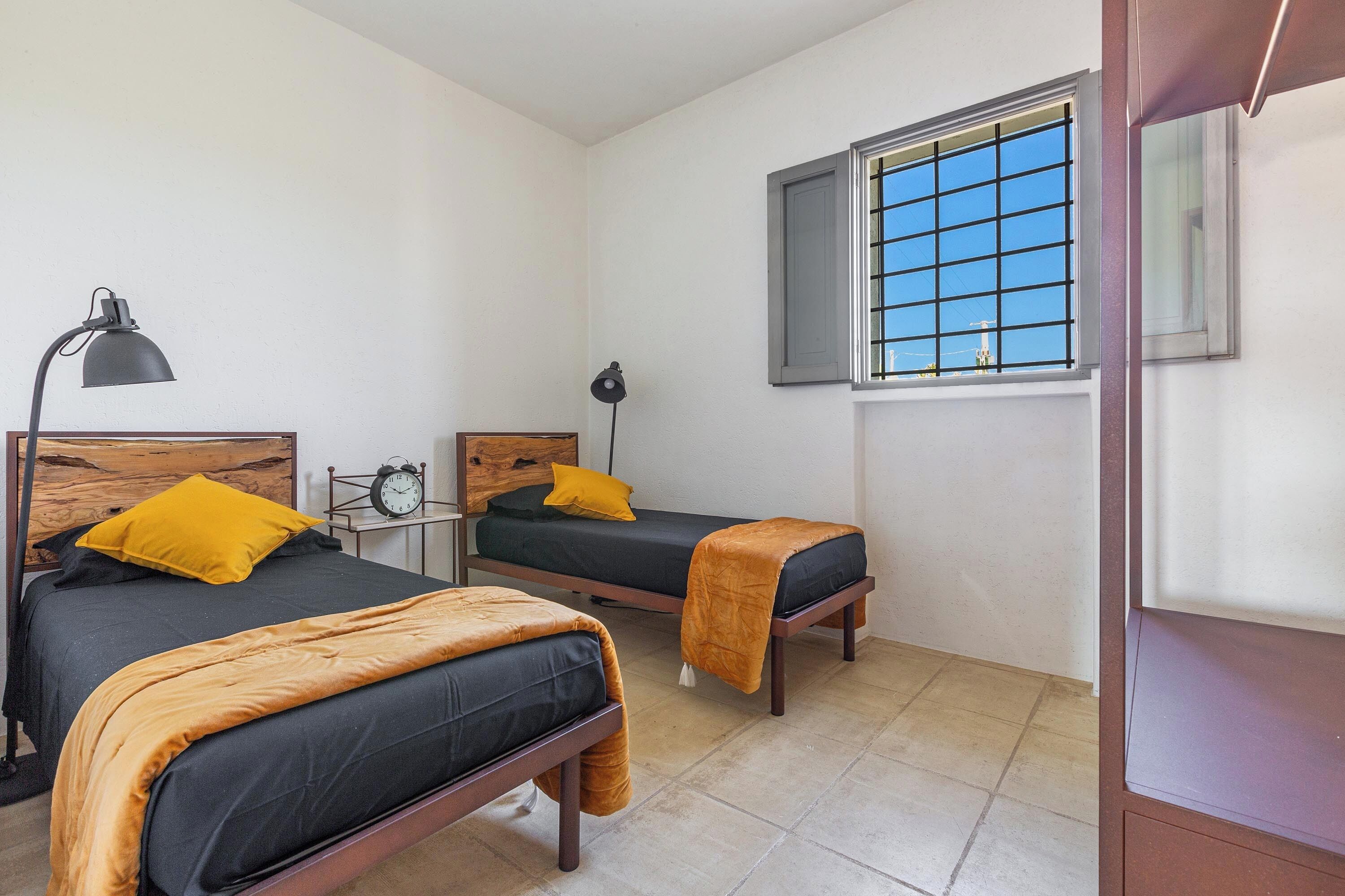 Un dormitorio con dos camas, una ventana de diseño celosía y un reloj en la pared.