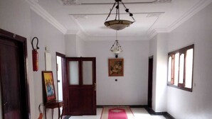 A hallway with a red carpet, a ceiling fan, and a framed picture on the wall. - Hotel Azaghar (M'rirt)