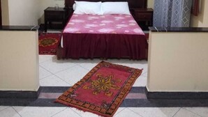 A bedroom with a bed, a television mounted on the wall, a ceiling light, and a patterned curtain. - Hotel Azaghar (M'rirt)