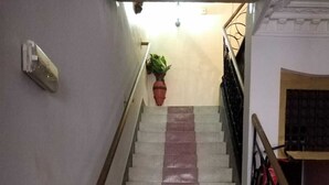 A staircase with alternating white and pink steps, a metal handrail, a potted plant at the top, and a metal railing on the right. - Hotel Azaghar (M'rirt)