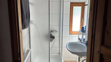 A bathroom with a shower, toilet, sink, and a window.