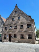 A stone building with multiple windows and a sign reading "Alstodilkhuis."