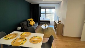 A modern living room with a dining area, featuring a sofa, a coffee table, and a dining table set with yellow placemats and cutlery. - Modular Suites Alfonso Gomez (Madrid)