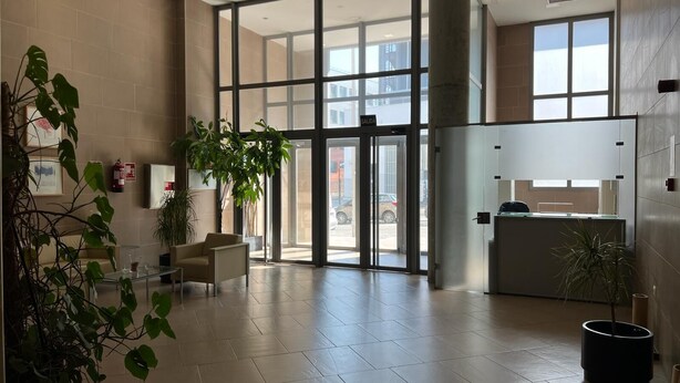 A spacious lobby with a reception desk, large glass doors, and multiple potted plants. - Modular Suites Alfonso Gomez (Madrid)