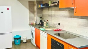 A compact kitchen with a refrigerator, washing machine, dishwasher, and an oven. - Modular Suites Alfonso Gomez (Madrid)