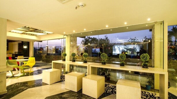 A modern lobby with a glass partition, seating areas, and a view of the outside. - Hotel Art Boutique (Hyderabad)