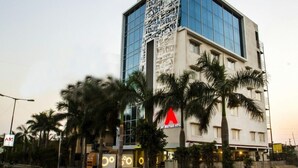 A modern hotel with a glass facade, palm trees in the foreground, and a sign for the Art Boutique Hotel. - Hotel Art Boutique (Hyderabad)