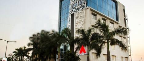 A modern hotel with a glass facade, palm trees in the foreground, and a sign for the Art Boutique Hotel.