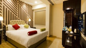 A hotel room with a bed, a TV, a minibar, and a large mirror. - Hotel Art Boutique (Hyderabad)