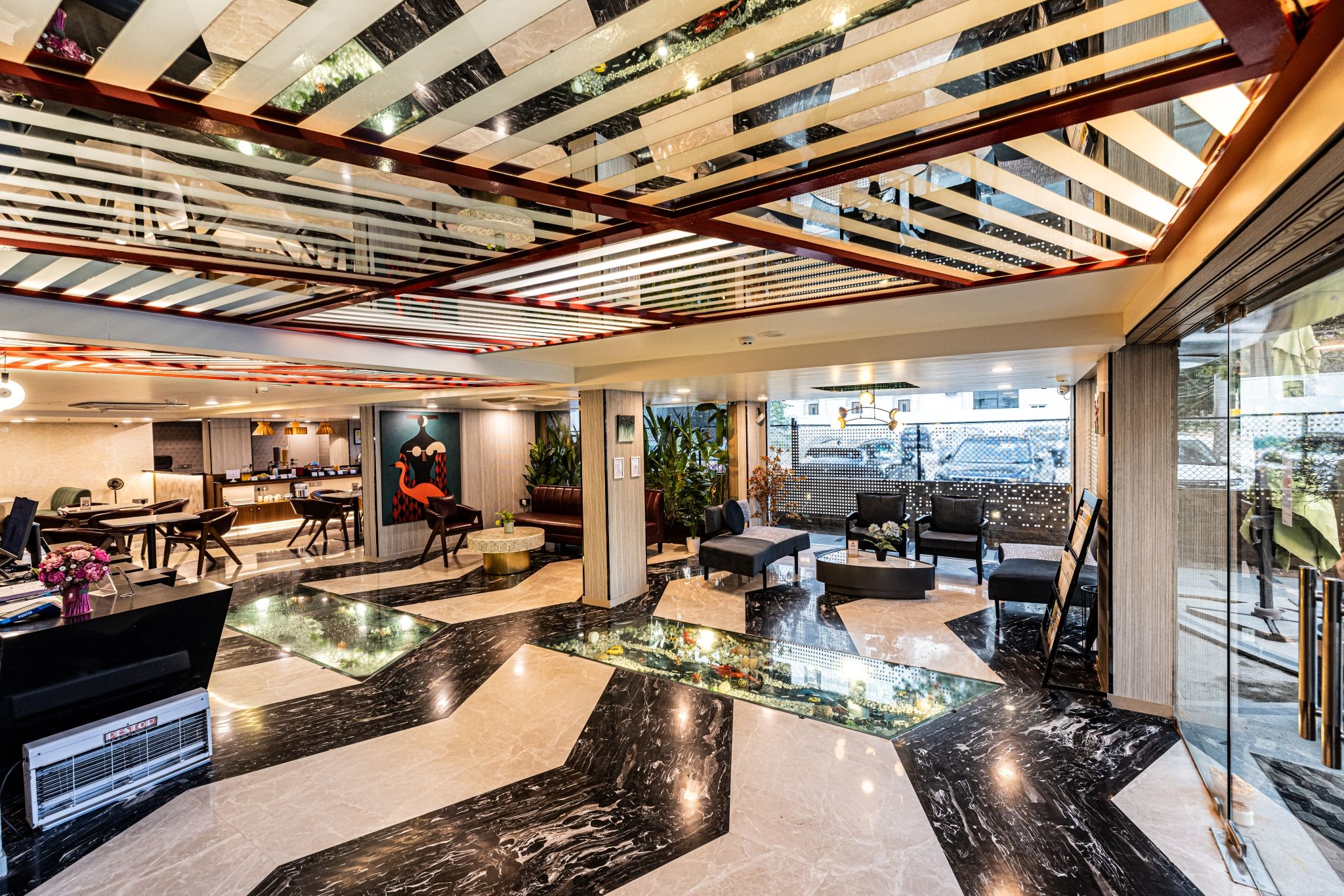 A modern hotel lobby with a glass coffee table, seating area, and a reception desk.
