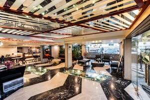 Un moderno vestíbulo de hotel con una mesa de centro de vidrio, zona de estar y mostrador de recepción.