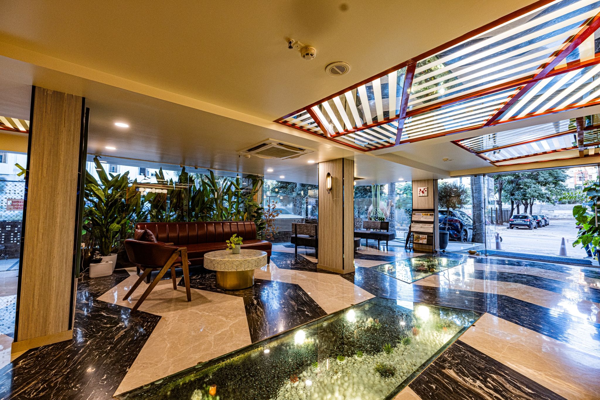 Un vestíbulo moderno con zona de estar, mostrador de recepción y una fuente de agua de cristal.