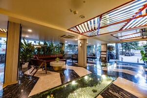 Eine moderne Lobby mit Sitzgelegenheit, einer Rezeption und einer Wasserspüle aus Glas.