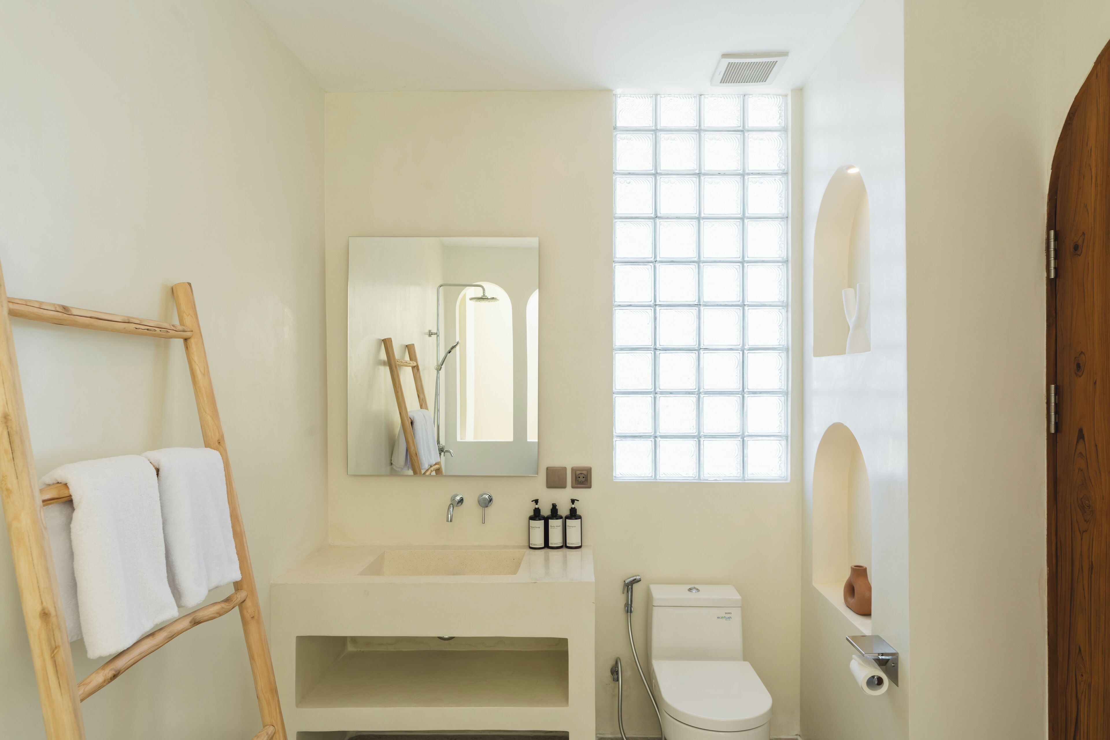 A bathroom with a wooden ladder, a sink, a toilet, and a window with a grid pattern.