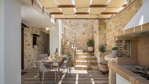 A dining area with a stone wall, a staircase, and potted plants. - D'Oro Villas (Kissamos)