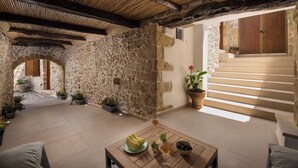 A stone-walled patio with a wooden table, potted plants, and a staircase leading to an upper level. - D'Oro Villas (Kissamos)