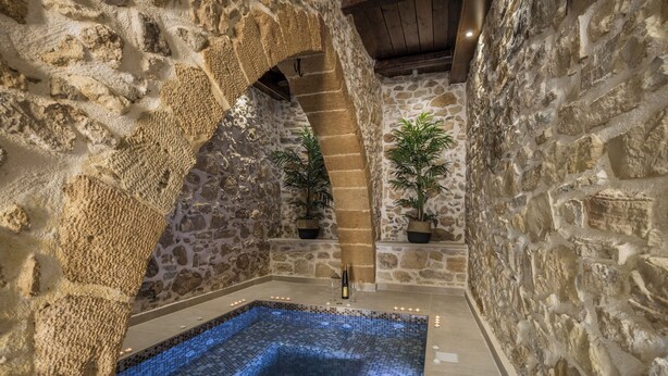 A stone-walled indoor pool area with a tiled floor and a small waterfall feature. - D'Oro Villas (Kissamos)