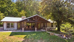 Une cabane dotée d’un patio couvert, d’un foyer et d’une cheminée en pierre.