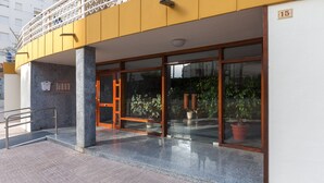 A hotel entrance with a glass door, a metal handrail, and a potted plant outside. - Gourmet in Grau i Platja (Gandia)
