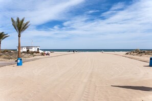 A wide sandy beach with palm trees and a small white building. - Gourmet in Grau i Platja (Gandia)