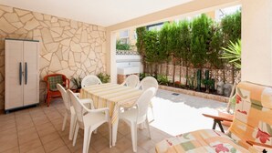 A patio area with a table and chairs, a refrigerator, and a small seating area with a cushion. - Llam Ntol in Oliva With 3 Bedrooms and 1 Bathrooms (Oliva)