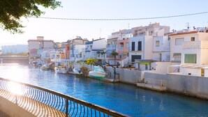 A canal with boats docked, surrounded by buildings with balconies and a clear sky. - Oreneta in Grau i Platja (Gandia)