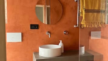 Un baño con un espejo redondo, un lavabo blanco, una toalla amarilla y un inodoro.