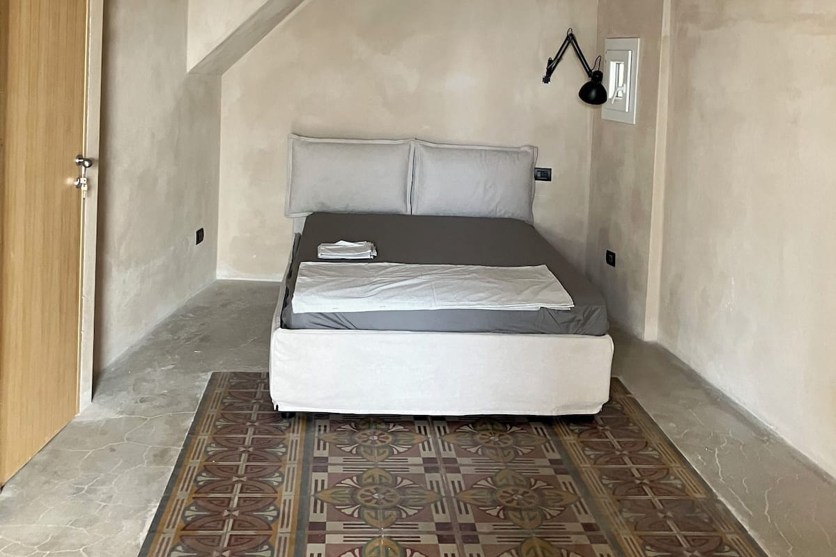 A bedroom with a bed, a patterned rug, and a sloped ceiling.
