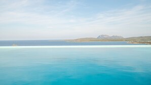 A coastal view with clear blue waters, a distant mountain, and a small island. - Giotto In Sardegna With Shared Pool (Olbia)