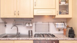 A kitchen with wooden cabinets, a stainless steel sink, a gas stove, and a coffee maker. - Giotto In Sardegna With Shared Pool (Olbia)