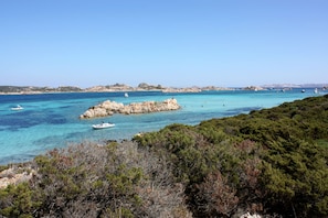 A coastal landscape with rocky outcrops, clear turquoise waters, and boats.