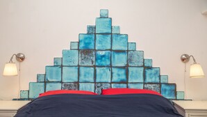 A bed with a blue mosaic headboard, red and black bedding, and bedside lamps on nightstands. - Giotto In Sardegna With Shared Pool (Olbia)