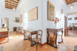 A spacious room with a high ceiling, wooden furniture, and a large painting on the wall. - Posada De La Casa Del Pintor Hab Jaen (Carmona)