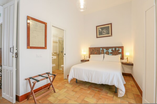 A bedroom with a bed, bedside tables, a mirror, and a door leading to a bathroom.