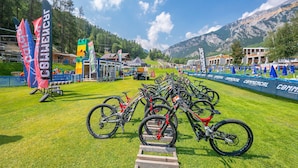 A mountain biking event with multiple bicycles lined up on a grassy field, tents, and flags in the background. - L Aquila Campo Smith On The Ski Slopes (Bardonecchia)