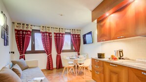 A compact kitchen with wooden cabinets, a dining table, and a sofa. - L Aquila Campo Smith On The Ski Slopes (Bardonecchia)