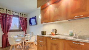 A modern kitchen with wooden cabinets, a stainless steel sink, and a dining area with a table and chairs. - L Aquila Campo Smith On The Ski Slopes (Bardonecchia)