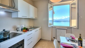 Une cuisine moderne avec des meubles blancs, une cuisinière encastrée et une fenêtre donnant sur la mer.