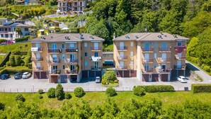 Un immeuble résidentiel doté de nombreux balcons, d’un espace de stationnement et d’une végétation luxuriante qui entoure la propriété.