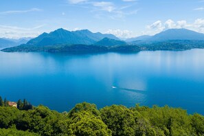 A lake with mountains in the background and a boat on the water. - The Golden View in Olbia (Belgirate)