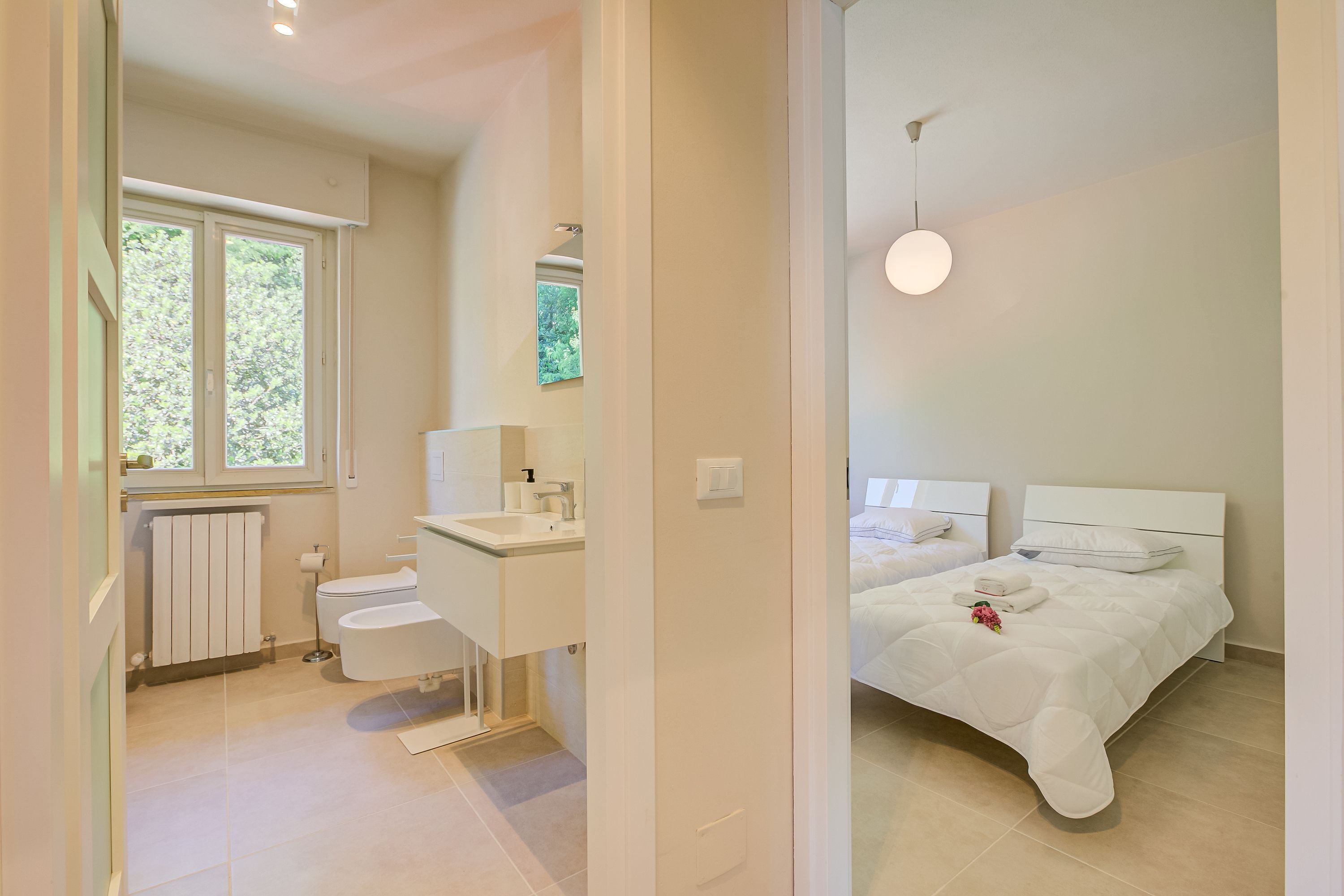 A modern bathroom with a toilet, sink, and window.