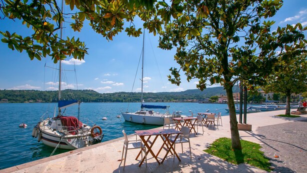 A waterfront area with boats docked, outdoor seating, and a view of the water and hills in the background. - Ricomilla Holiday-finestra Sul Verde- (Roe Volciano)