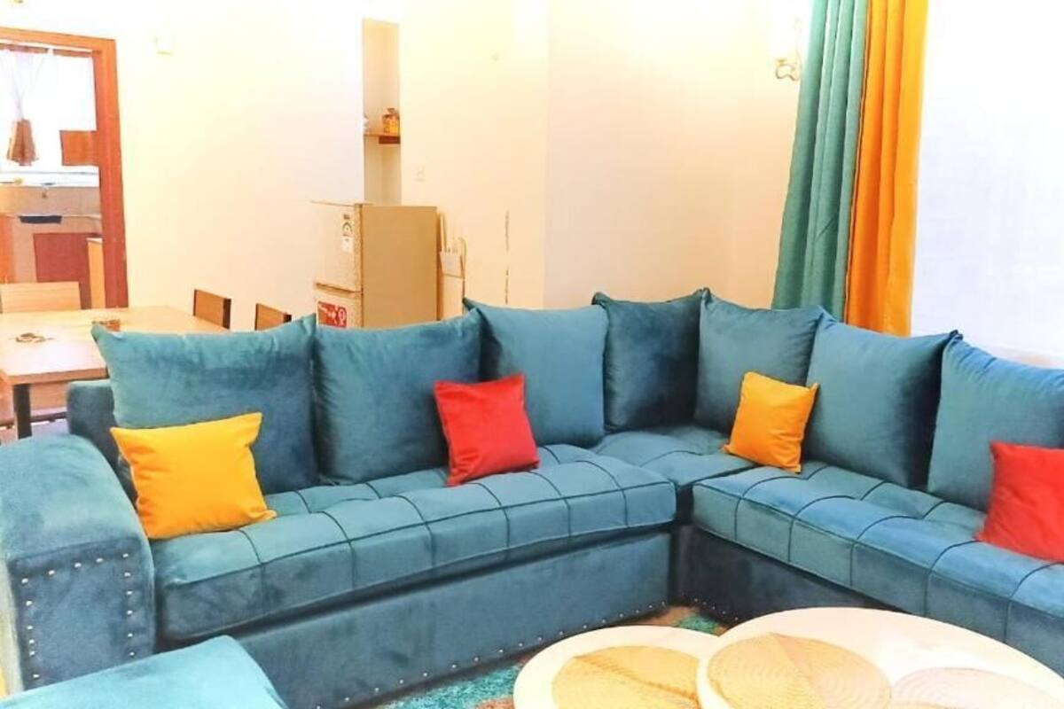 A living room with a sectional sofa, a round coffee table, and a dining area with a table and chairs.