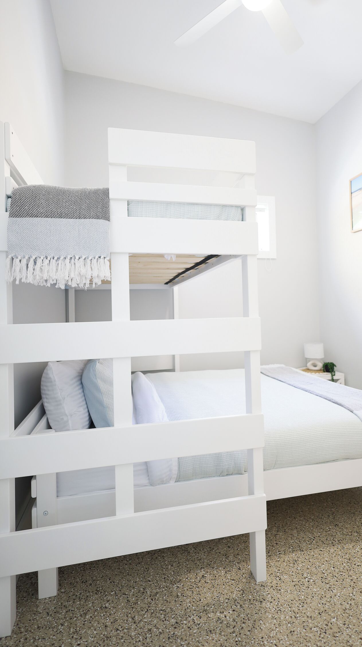 A bunk bed with white bedding and a ceiling fan.
