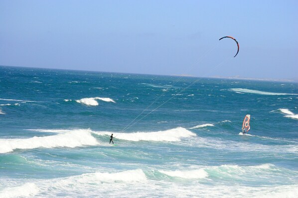 A beach with waves and a person windsurfing. - Su Entu in Palau With 1 Bedrooms and 1 Bathrooms (Palau)