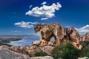 A natural rock formation with a large arch, surrounded by greenery and overlooking a coastal landscape. - Su Entu in Palau With 1 Bedrooms and 1 Bathrooms (Palau)